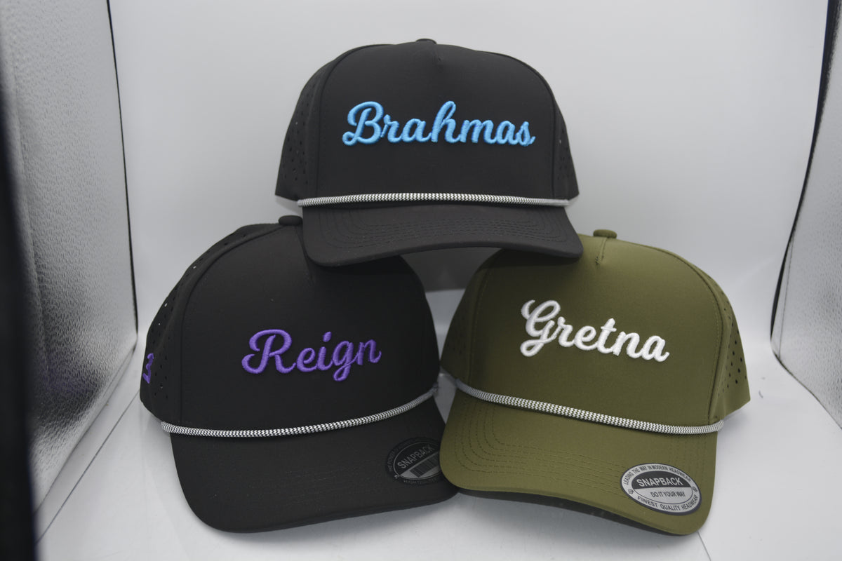 Three baseball caps with embroidered names on a white surface.